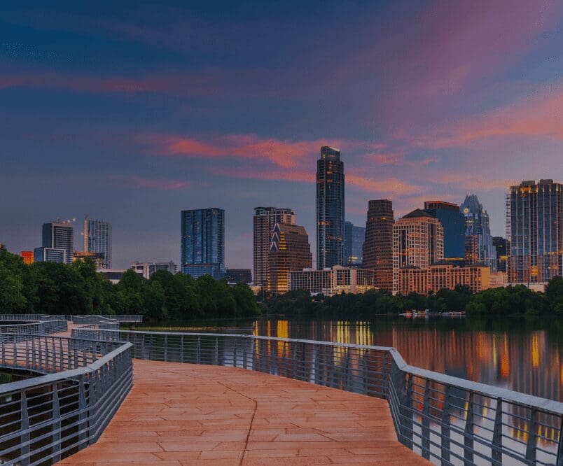 City skyline at sunset over a river.